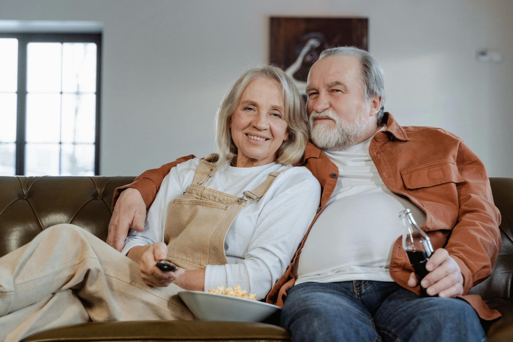 Adultos mayores sentados en el sofá viendo la TV. Pañales para adultos. - Pañales desechables para adultos - Pañales predoblados para adulto - Cubrecama desechable - Pañal cubrecama - Pañales cubrecama Adulto- pañales para adultos